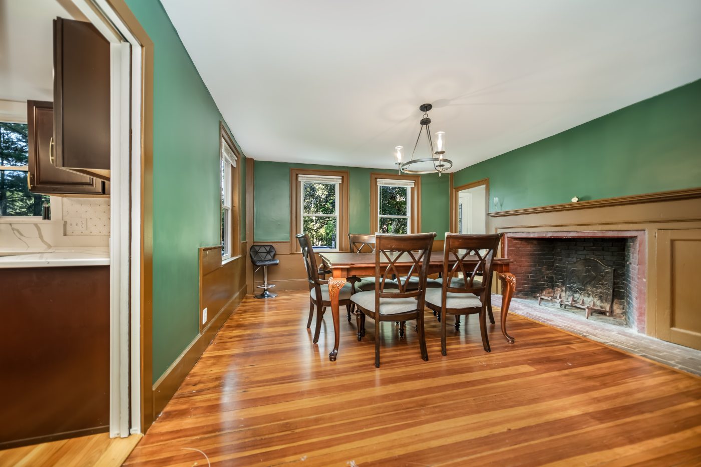 Dining room with a fireplace, panelled wainscot and green walls