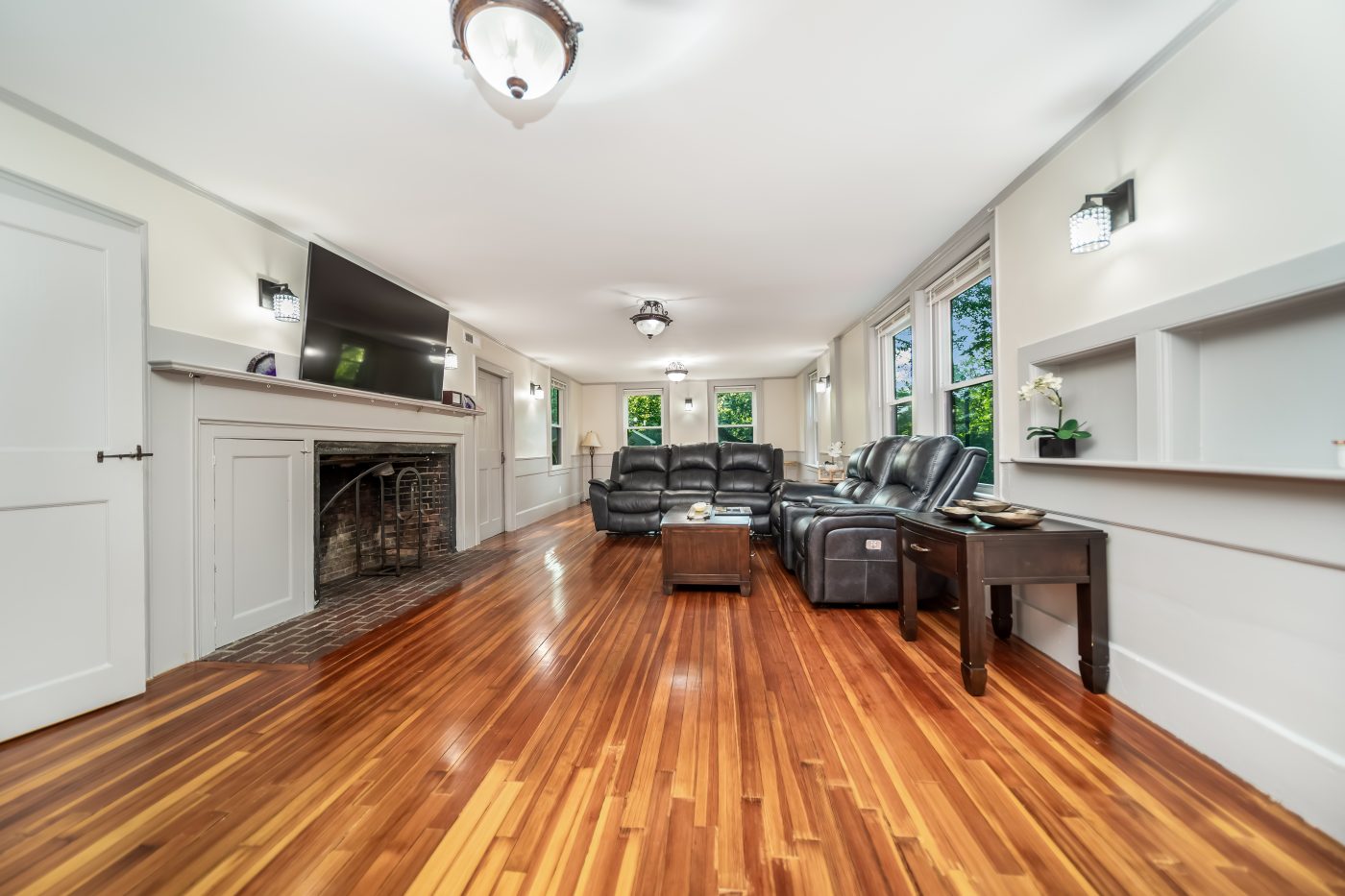A long living room with fireplace and hardwood floors