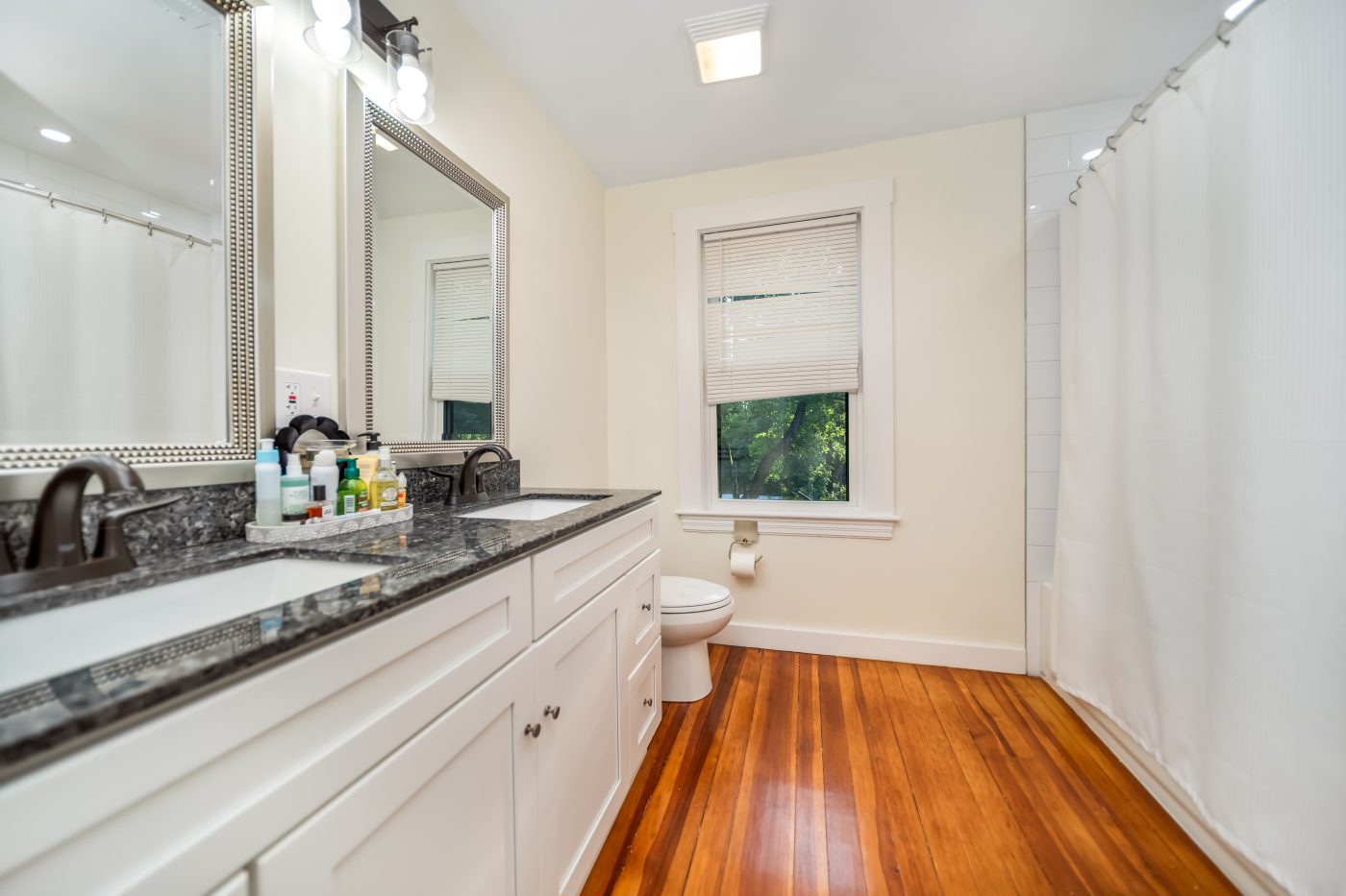 A full bathroom with a stone-topped vanity and glass shower