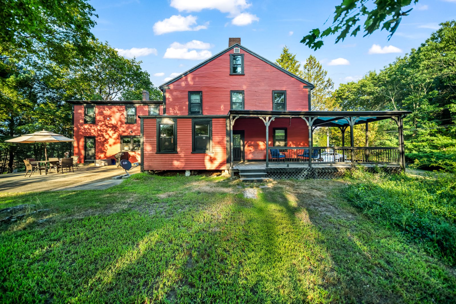 The rear elevation of The Elms, with the patio, the side ell and the long covered porch